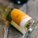 Wine bottle with an orange cap labeled 'SOU' on a stone surface.