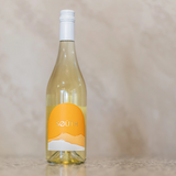 Bottle of white wine with an orange label on a beige background